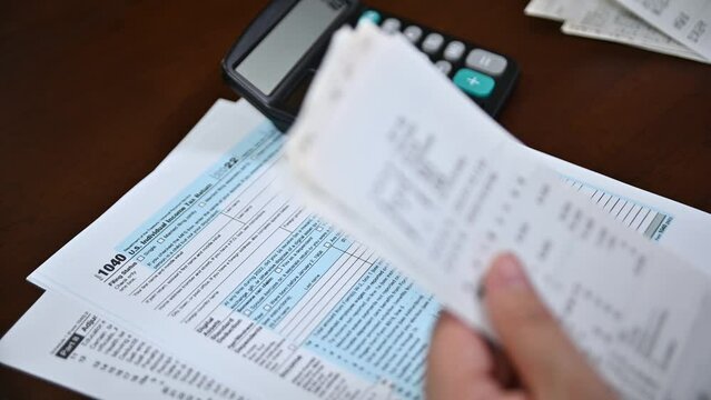 A man organizing individual income tax return form 1040 and receipts. Blurred background. Tax time.Tax concept. Close-up.