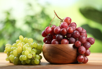Different fresh ripe grapes on wooden table against blurred background, closeup