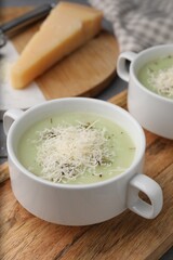 Delicious cream soup with parmesan cheese in bowls on table