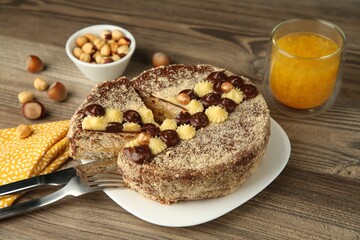 Delicious Kyiv Cake decorated with cream and hazelnuts served on wooden table