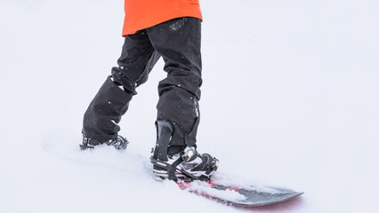 Legs of a man on a snowboard against the background of white snow