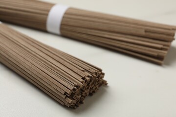 Uncooked buckwheat noodles (soba) on white marble table, closeup