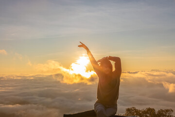 Woman raised hands enjoying Morning fog - foggy mist on mountains peaks.silhouette