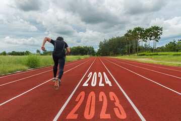 The start into the new year 2024. Start up of runner woman running on nature race track go to Goal...