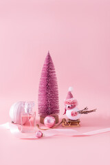 New Year's presentation of the fragrance of women's perfume in a chic bottle on a pink background among decorative New Year's elements. Vertical view.