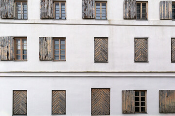.A white building wall with many horizontal windows and wooden shutters on it