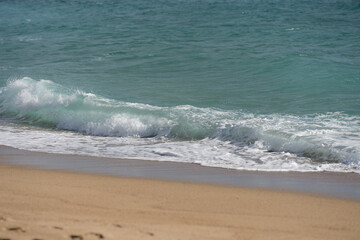 Waves rolling on a sandy beach on a sunny day