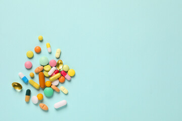 Many different pills on light blue background, flat lay. Space for text