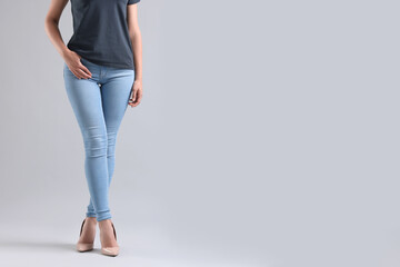 Woman wearing stylish jeans and high heels shoes on light gray background, closeup. Space for text
