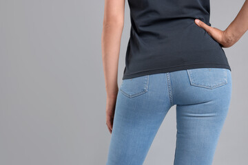 Woman wearing stylish jeans on light gray background, closeup. Space for text