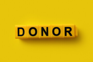 Word Donor made of cubes on yellow background, top view