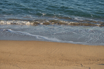 Waves rolling on a sandy beach on a sunny day