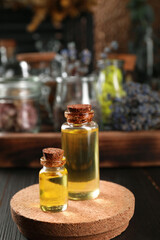 Bottles with herbal essential oils on wooden table. Space for text