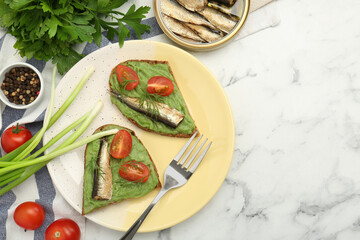 Delicious sandwiches with sprats, tomatoes, avocado puree and dill served on white marble table, flat lay. Space for text