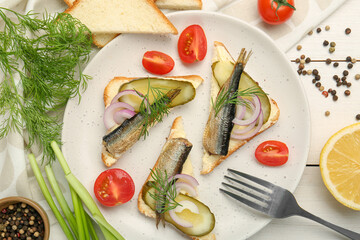Delicious sandwiches with sprats, pickled cucumber, onion and dill served on white wooden table, flat lay