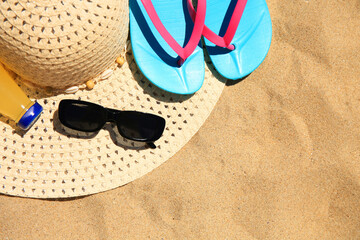 Fototapeta na wymiar Straw hat, sunglasses, flip flops and refreshing drink on sand, flat lay with space for text. Beach accessories