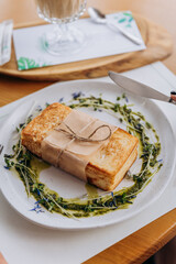 Tasty sandwich with ham and cheese decorated by pesto sauce and greens. Breakfast restaurant menu