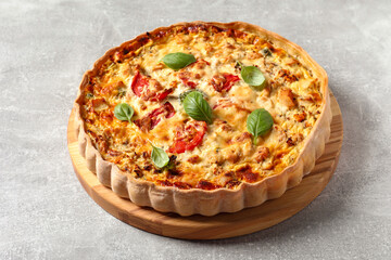 Tasty quiche with tomatoes, basil and cheese on light table
