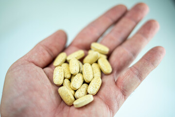 A hand shows various vitamin and supplement pills