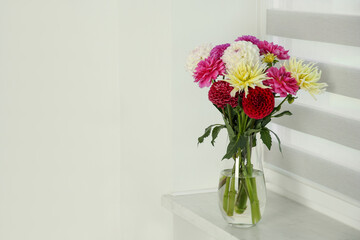 Bouquet of beautiful Dahlia flowers in vase on windowsill indoors. Space for text