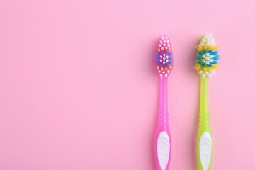 Colorful plastic toothbrushes on pink background, flat lay. Space for text