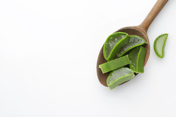 Wooden spoon with fresh aloe vera pieces on white background, top view. Space for text