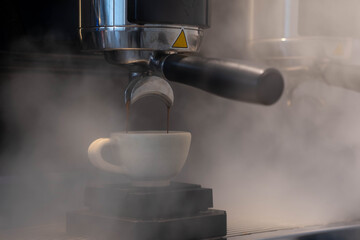 A Shot of Espresso  from Espresso Coffee Machine with Steam from the machine