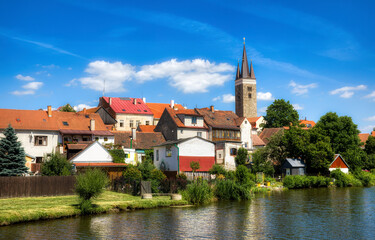 Fototapeta na wymiar Houses in Beautiful Telc by the Lake Ulicky Rybnik in the Czech Republic, with the Tower of the Church of the Holy Spirit