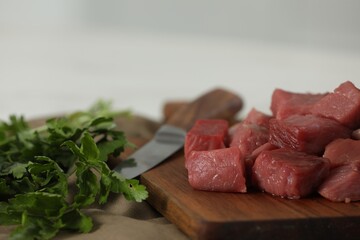 Pieces of raw beef and parsley on table, closeup