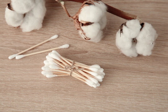 Cotton swabs and flowers on wooden table, closeup