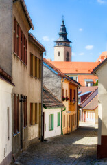 Fototapeta na wymiar Narrow, Cobbled Street in Telc in the Czech Republic, with the Towers of the Church of St James
