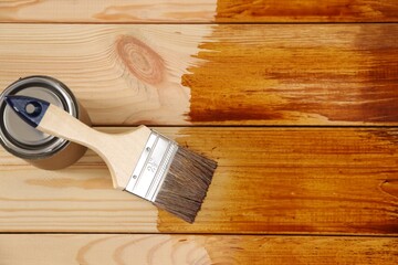 Brush and can with wood stain on wooden surface, top view. Space for text