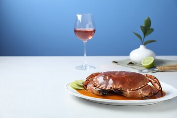 Delicious crab with sauce and lime on white table against light blue background. Space for text