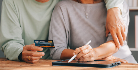 Obraz na płótnie Canvas Shocked aged couple become victims of online fraud using credit card phone to pay for goods order service online on suspicious website. Frustrated older spouses overspending money at internet shopping
