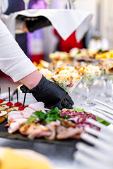 hands of a waiter prepare food for a buffet table in a restaurant