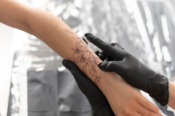 tattoo artist in black gloves applying cream on woman's arm