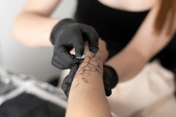 tattoo artist in black gloves applying cream on woman's arm