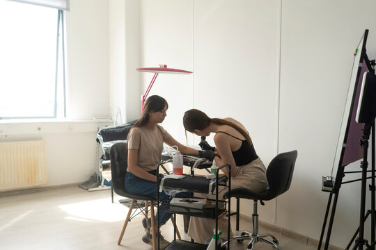 tattoo studio workshop minimalistic interior, female tattooist working with young girl