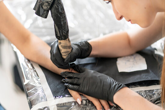 a Cropped shot of tattoo artist working at his studio tattooing sleeve on the arm of female client