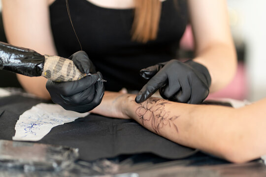 a Cropped shot of tattoo artist working at his studio tattooing sleeve on the arm of female client