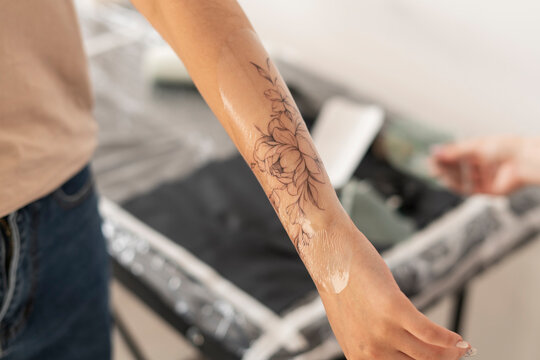 young woman in tattoo studio looking at her new flower tattoo in her arm