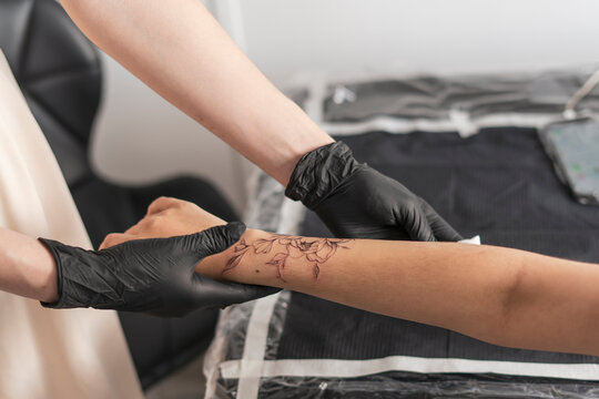 young woman in tattoo studio looking at her new flower tattoo in her arm