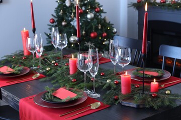 Elegant Christmas table setting with dishware and burning candles in festively decorated room