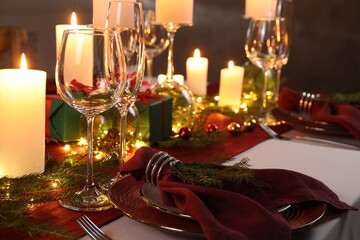 Christmas table setting with burning candles and festive decor