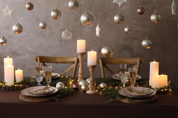 Christmas table setting with burning candles and festive decor