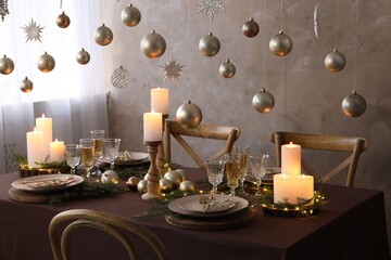 Christmas table setting with burning candles and festive decor