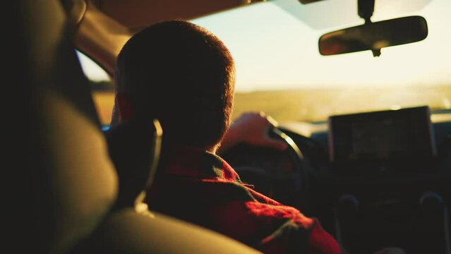 Rear view in saloon auto on male who driving on rural road. Blurred view from front window car and rear view inside mirror. Summer travel by transport outside city on uneven sections bumps and pits.