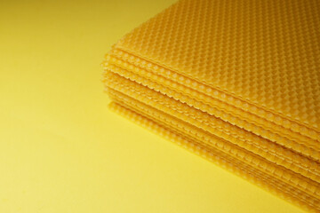 Beeswax honeycomb candle sheets on yellow background. Side view. Space for text.