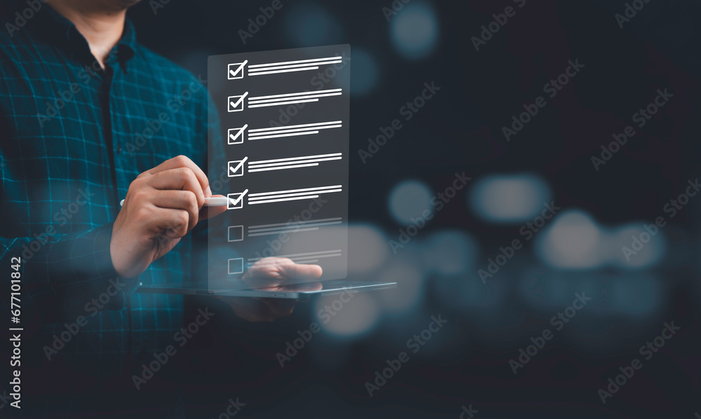 Poster Businessman using pen to tick correct sign mark on virtual checklist for quality control and assurance of ISO concept.