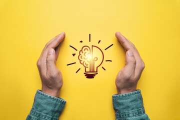 Two hand protect glowing lightbulb on yellow background for  prevent patent and idea of problem...